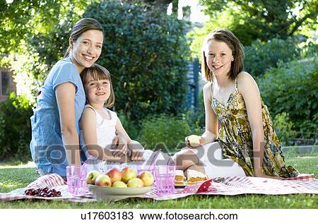 Stock Image - Happy mother and daughters at picnic. Fotosearch