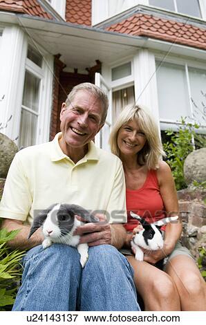 Stock Photo - Happy seniors hold rabbits. Fotosearch