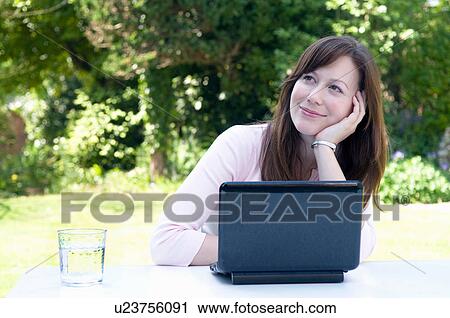 Stock Image - Happy woman daydreams in garden. Fotosearch
