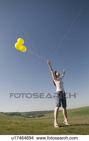 Picture - Happy woman on hill with balloons. Fotosearch