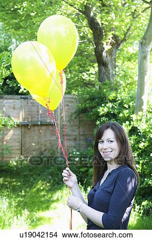 Picture - Happy woman with balloons in garden. Fotosearch