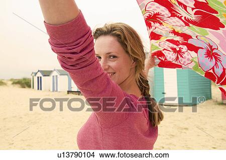 Happy women on beach holds towel in wind View Large Photo Image Picture - Happy women on beach holds towel in wind. Fotosearch
