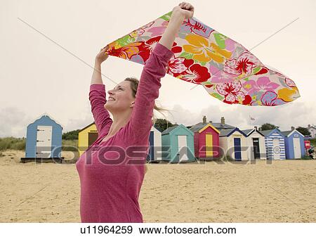 Happy women on beach holds towel in wind View Large Photo Image Stock Photo - Happy women on beach holds towel in wind. Fotosearch