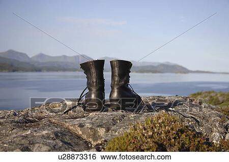 Stock Photograph - Hiking boots on cliff by the sea. Fotosearch