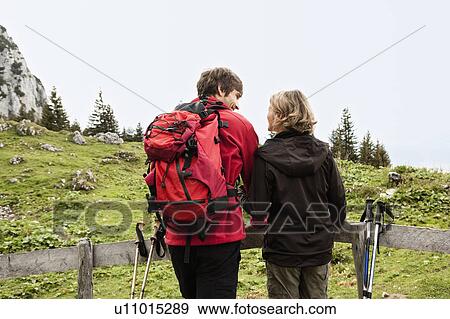 Hiking couple resting on fence View Large Photo Image Stock Photo - Hiking couple resting on fence. Fotosearch