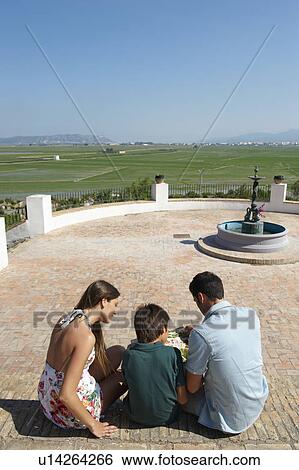 Stock Photograph - Holidaying family reading map. Fotosearch