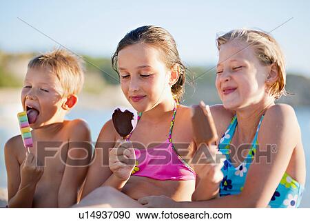 Stock Image - Kids eating ice cream at the beach. Fotosearch