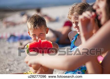Kids eating watermelon at the beach View Large Photo Image Stock Photograph - Kids eating watermelon at the beach. Fotosearch