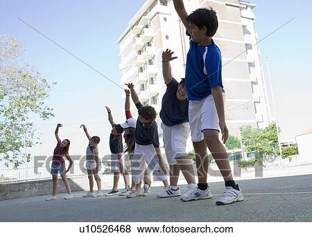 Stock Photo - Kids on a soccaryard doing warmup. Fotosearch