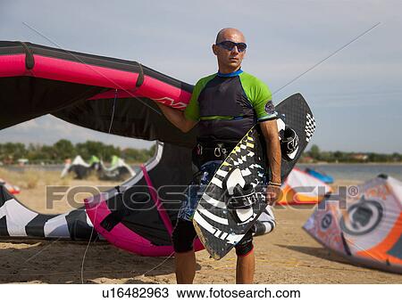 Stock Image - Kitesurfer holding kite and board. Fotosearch