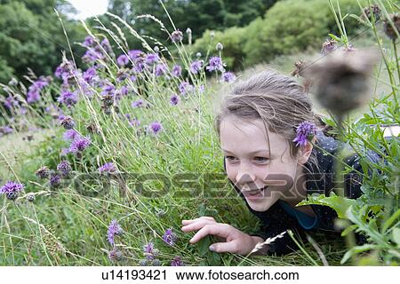 Stock Image - Little girl peeks thru grass. Fotosearch