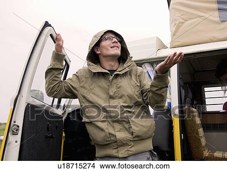 Picture - Male camper feels for the rain. Fotosearch