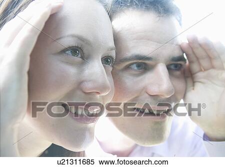 Stock Photography - Man and woman look thru window. Fotosearch