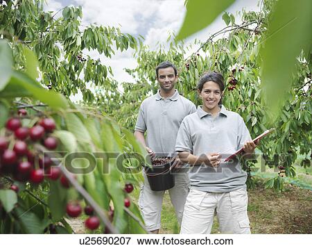 Stock Photo - Man and woman posing in cherry orchard. Fotosearch