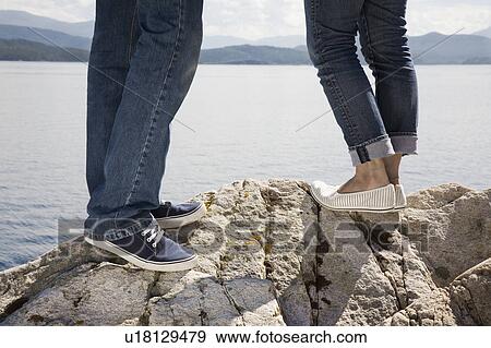 Man and woman standing on rock by sea View Large Photo Image Stock Photo - Man and woman standing on rock by sea. Fotosearch