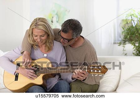 Stock Photography - Man and woman strumming guitar. Fotosearch