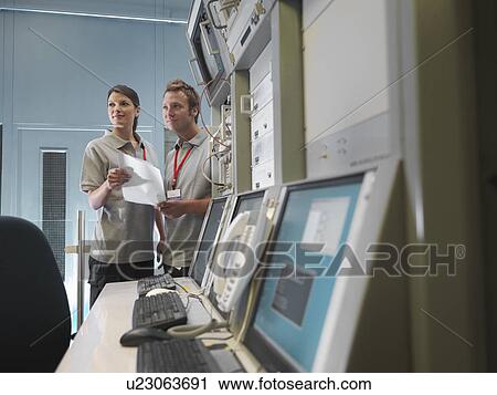 Stock Image - Man and woman work at control desk. Fotosearch
