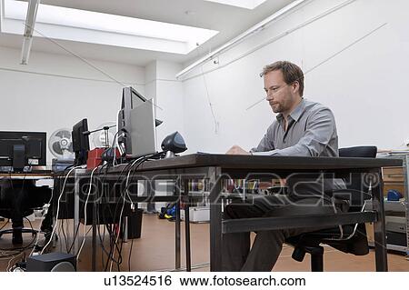 Stock Photograph - Man at desk in design office. Fotosearch