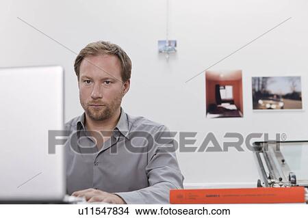 Man at desk on his laptop View Large Photo Image Picture - Man at desk on his laptop. Fotosearch