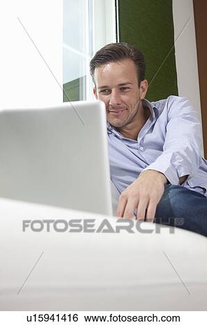 Stock Photograph - Man at home with laptob. Fotosearch