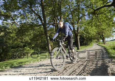Man cycling down a dirt road View Large Photo Image Stock Image - Man cycling down a dirt road. Fotosearch