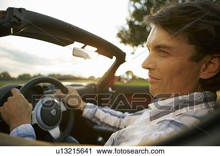 Stock Image - Man driving an electric sports car. Fotosearch