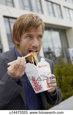Stock Image - Man eating chinese take away for lunch. Fotosearch