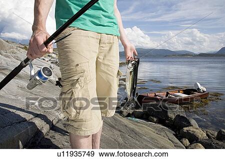 Stock Photo - Man holding fishing rod and mackerels. Fotosearch