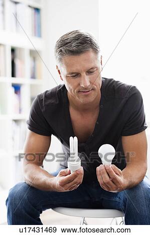 Stock Photo - Man holding light bulbs. Fotosearch