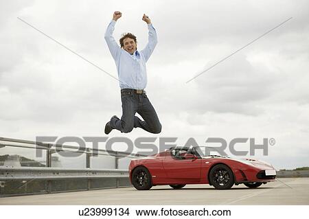 Man jumping happily over electric car View Large Photo Image Picture - Man jumping happily over electric car. Fotosearch