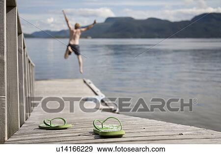 Man jumping off wooden jetty into sea View Large Photo Image Stock Photo - Man jumping off wooden jetty into sea. Fotosearch