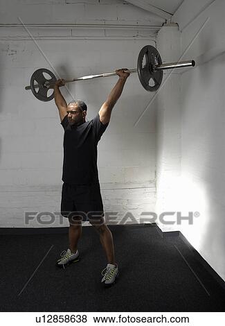Man lifting weights in a gym View Large Photo Image Stock Photo - Man lifting weights in a gym. Fotosearch