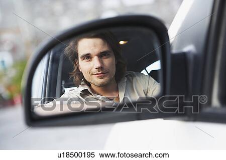 Stock Photography - Man looking at driving mirror. Fotosearch