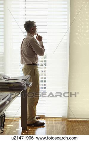 Stock Photograph - Man looking out of office window. Fotosearch