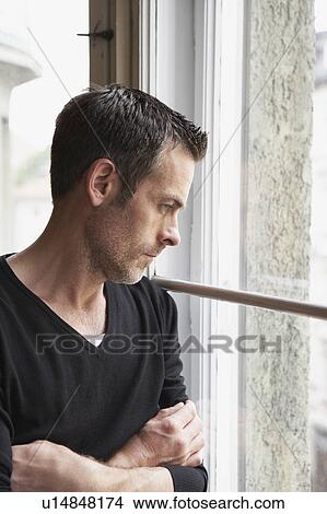Picture - Man looking out window. Fotosearch