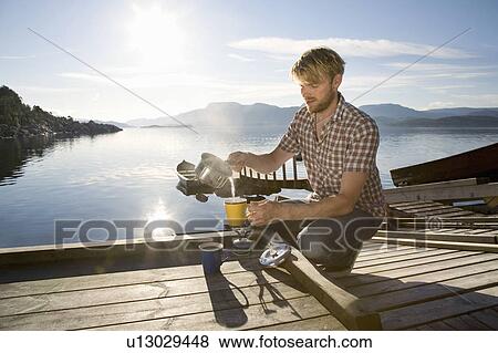 Man making coffee on jetty by sea View Large Photo Image Stock Photo - Man making coffee on jetty by sea. Fotosearch