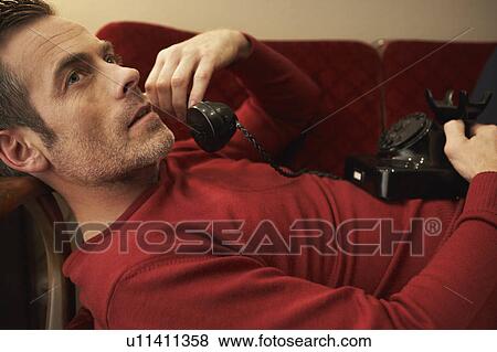 Man on couch using vintage phone View Large Photo Image Stock Photo - Man on couch using vintage phone. Fotosearch