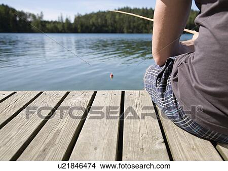 Picture - Man on jetty, fishing with bamboo rod. Fotosearch