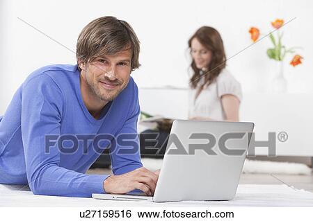 Man on laptop while woman reads View Large Photo Image Stock Photograph - Man on laptop while woman reads. Fotosearch