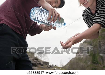 Man pouring water onto womans hands View Large Photo Image Stock Photo - Man pouring water onto womans hands. Fotosearch