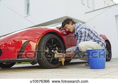 Stock Photograph - Man proudly cleaning his electric car. Fotosearch