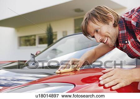 Stock Photo - Man proudly polishing hi electric car. Fotosearch