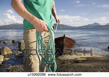 Stock Photograph - Man pulling wooden boat to shore. Fotosearch