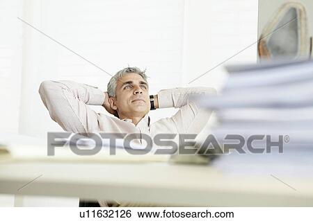 Stock Photograph - Man reclining behind desk. Fotosearch