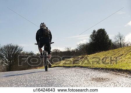 Man riding bike on countryside road View Large Photo Image Stock Image - Man riding bike on countryside road. Fotosearch