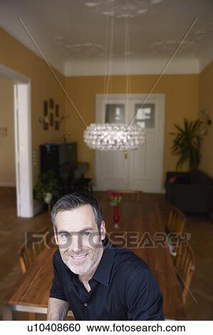 Stock Image - Man sitting in front of table. Fotosearch