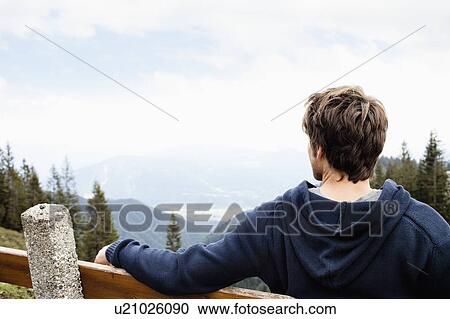 Man sitting on bench watching landscape View Large Photo Image Stock Image - Man sitting on bench watching landscape. Fotosearch