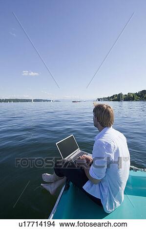 Man sitting with laptop by a lake View Large Photo Image Picture - Man sitting with laptop by a lake. Fotosearch