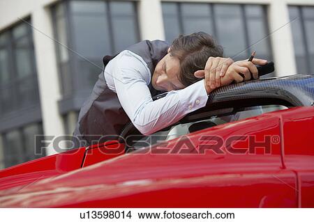 Picture - Man sleeping on his electric sports car. Fotosearch