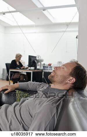 Stock Photo - Man sleeping on sofa at the office. Fotosearch
